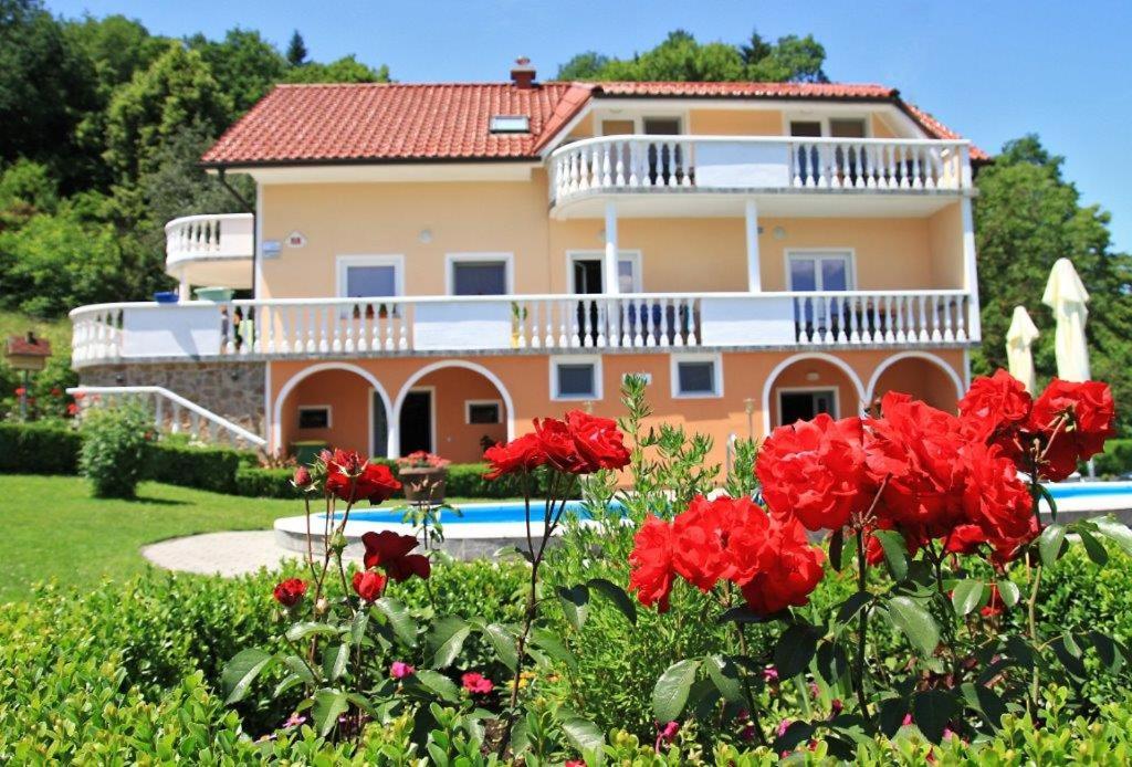 una casa con flores rojas delante de ella en Apartmaji in sobe Kocjančič en Podčetrtek