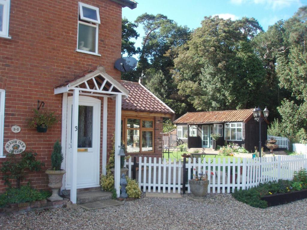a house with a white fence and a white door at Meadow Farm Cottage in Norwich