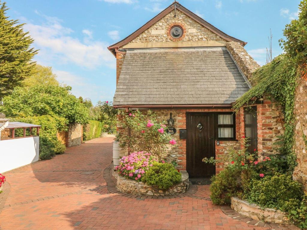 ein Backsteinhaus mit Blumen auf einer Ziegelsteinfahrt in der Unterkunft Coach Cottage in Colyton