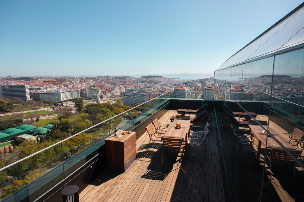 リスボンにあるインターコンチネンタル リスボンのテーブルと椅子が備わる建物の最上階からの景色を望めます。