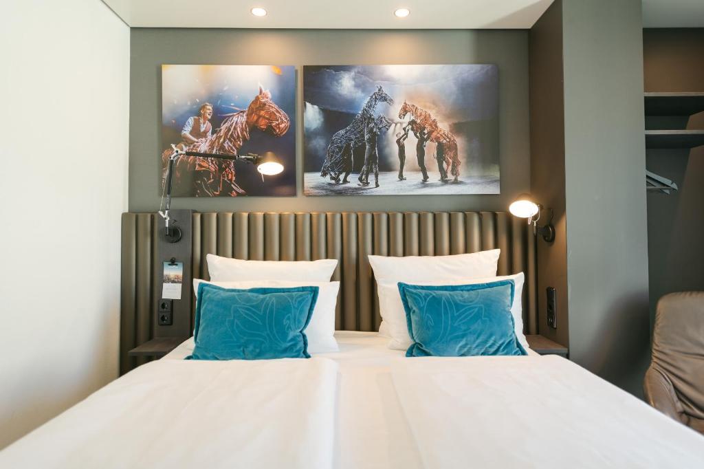 a bedroom with a large white bed with blue pillows at Motel One Berlin Ku'Damm in Berlin