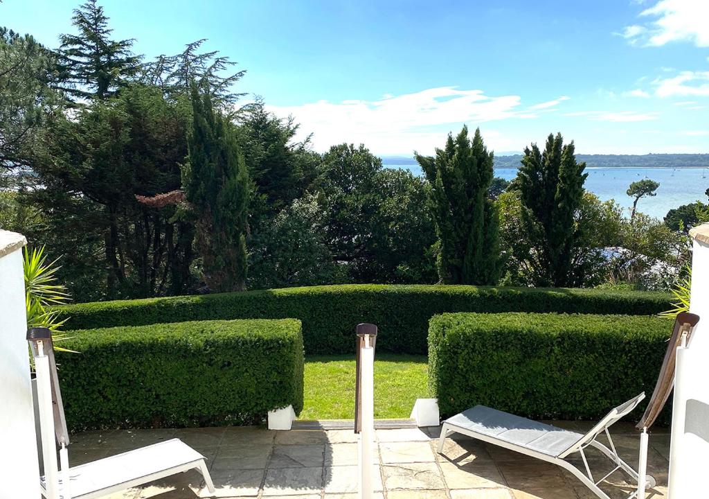 a patio with two chairs and a hedge at Harbour Heights Hotel in Poole