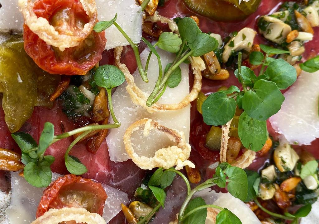 a close up of a pizza with tomatoes and vegetables at Harbour Heights Hotel in Poole