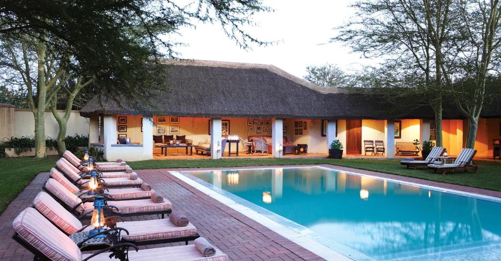 a house with a swimming pool with chaise lounges at Elephant House in Addo