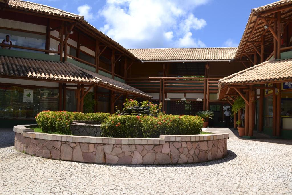 a building with a courtyard with flowers in front of it at Stúdio 1 Armazém da Vila in Praia do Forte