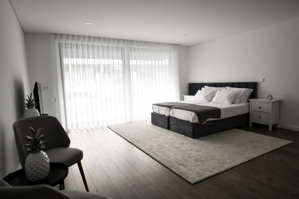 1 dormitorio con 1 cama, 1 silla y 1 ventana en PALHOTAS GUEST HOUSE - Apartamento Sé de Braga, en Braga