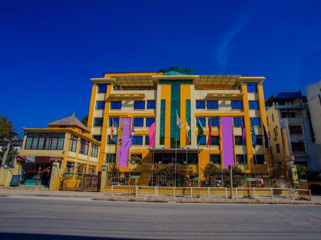 un grand bâtiment jaune avec des bannières roses devant lui dans l'établissement Yellow Pagoda Hotel, à Katmandou