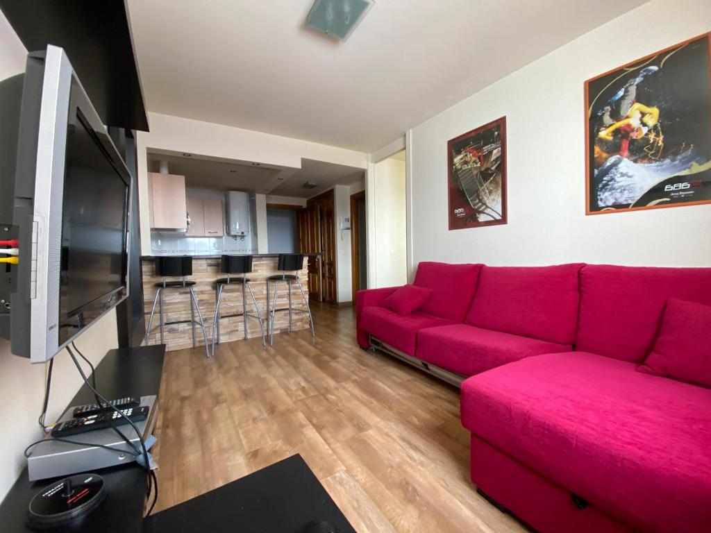 ein Wohnzimmer mit einem roten Sofa und einer Küche in der Unterkunft Apartamentos San Isidro in León