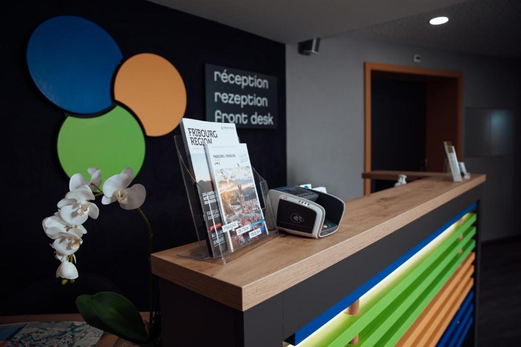 a reception desk with a clock on top of it at My Hotel Fribourg in Givisiez