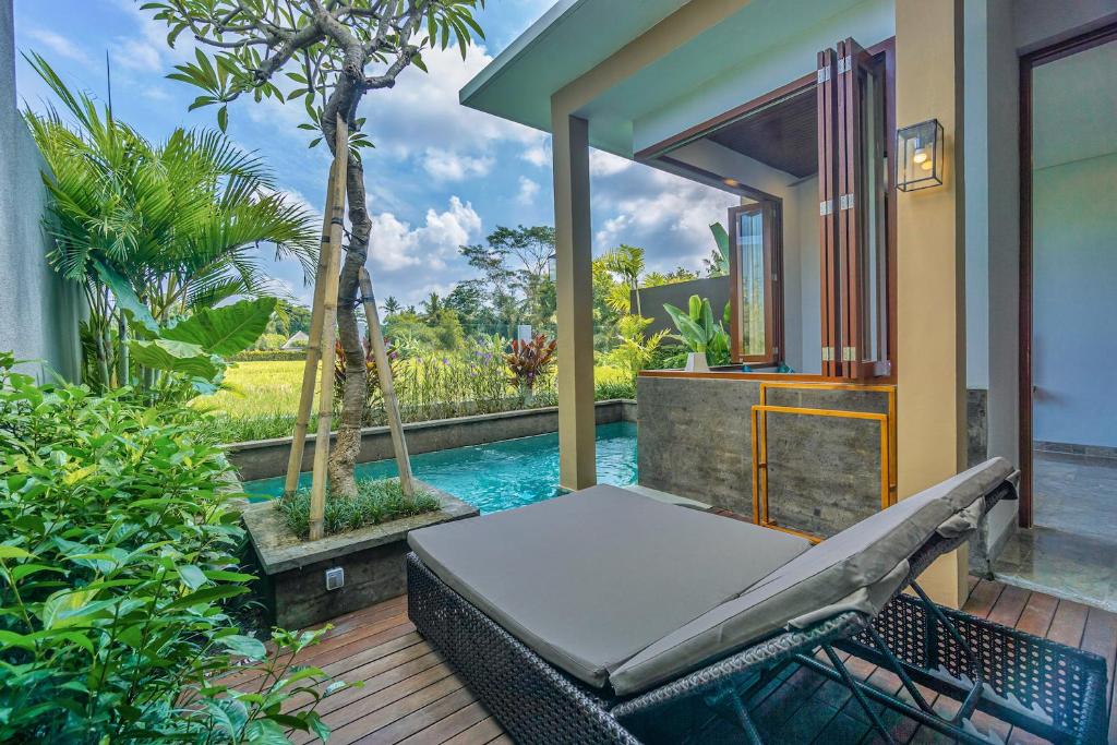 a patio with a bed and a swimming pool at Lavanya Ubud Romantic Villas in Ubud