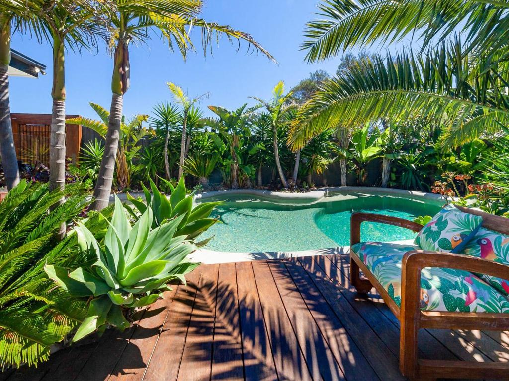 a swimming pool with a chair and palm trees at Como Palm Retreat in Rye