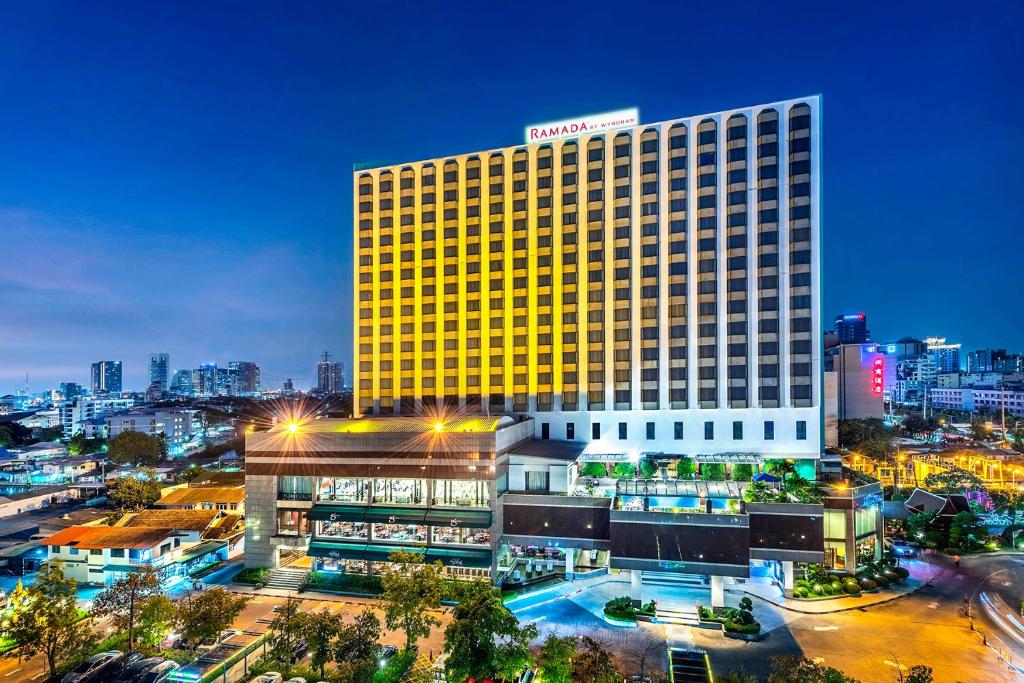 a large hotel building with a city in the background at Ramada by Wyndham Bangkok Chaophya Park in Bangkok