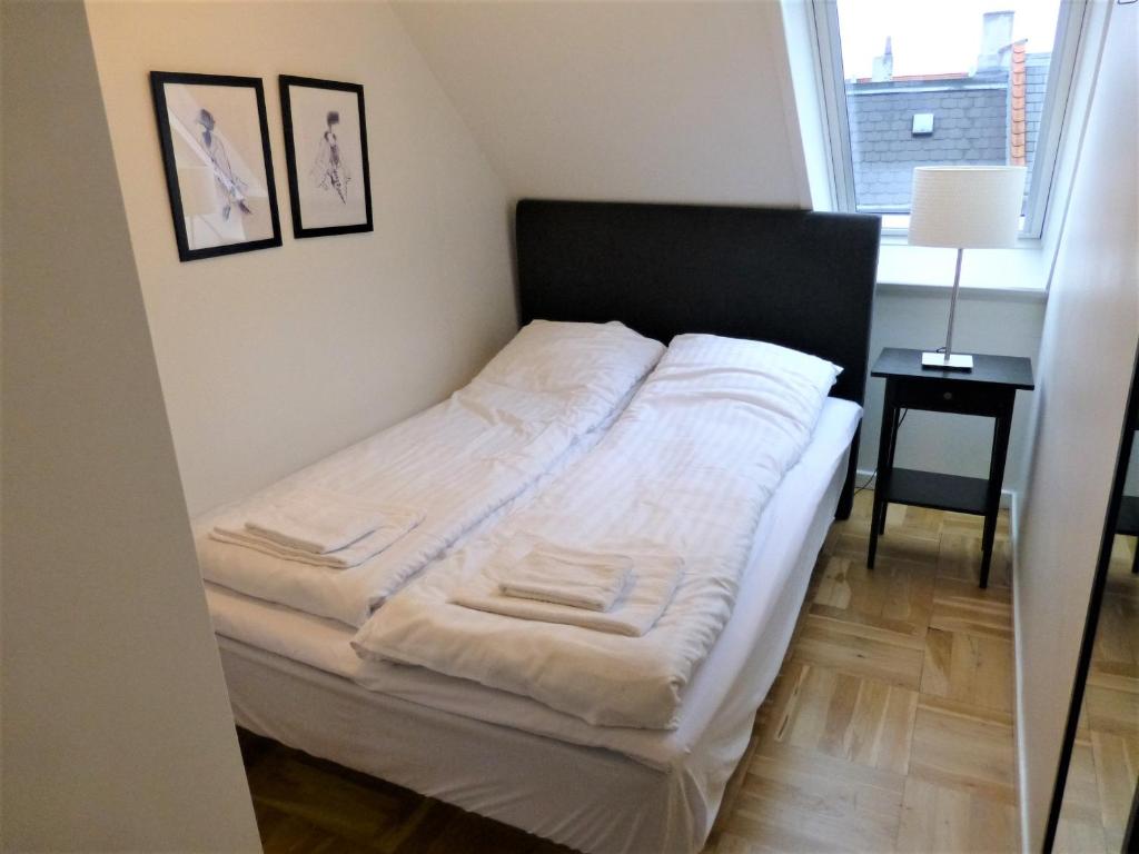 a small bedroom with a bed with white sheets at Cozy apartment in vibrant Nørrebro in Copenhagen