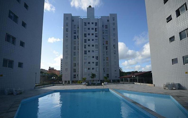 ein großer Pool vor einem hohen Gebäude in der Unterkunft Apartamento com piscina 1 quarto de até 6 pessoas - Guarujá in Guarujá