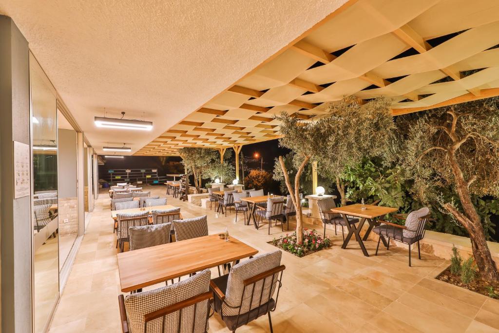 a restaurant with tables and chairs and trees at Hamarat Otel in Kaş