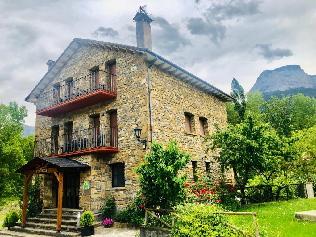 Edificio de piedra antiguo con porche y balcón en Casa Rural Sofia Ordesa en Escalona