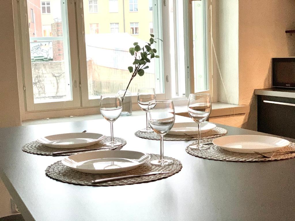 a table with plates and wine glasses on it at City Home Finland Ratina - Spacious Studio with Own SAUNA and Great Location Next to Uros Live Arena in Tampere