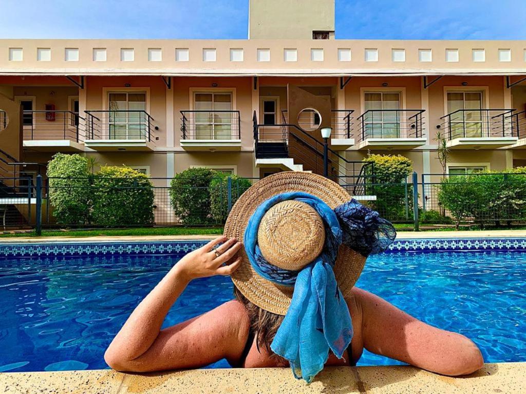 una mujer con sombrero sentada junto a una piscina en Mediterraneo Apart Hotel en Federación