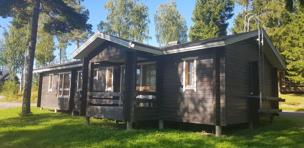 een kleine houten hut in een grasveld bij Riihivuori Cottages in Muurame