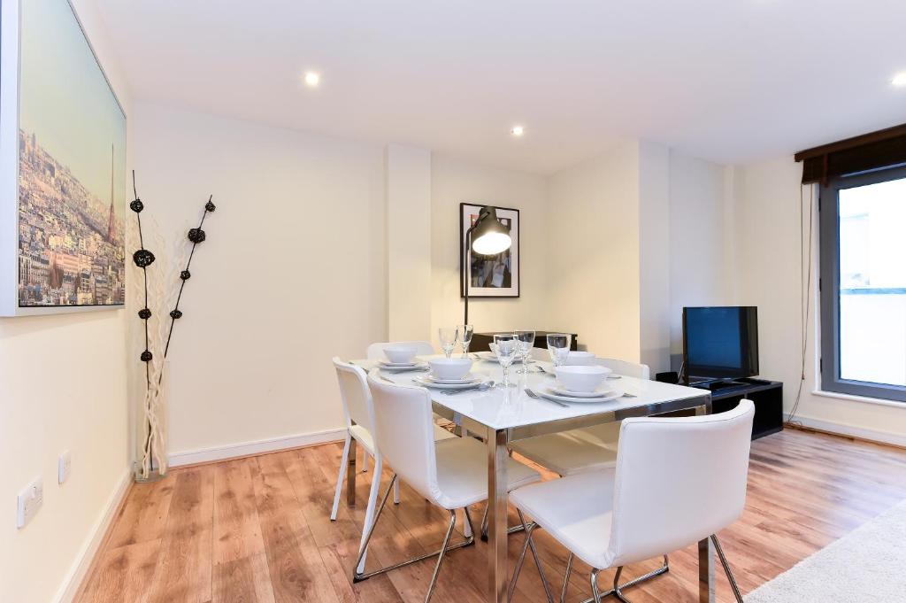 a dining room with a white table and white chairs at Bermondsey Central London Apartments in London
