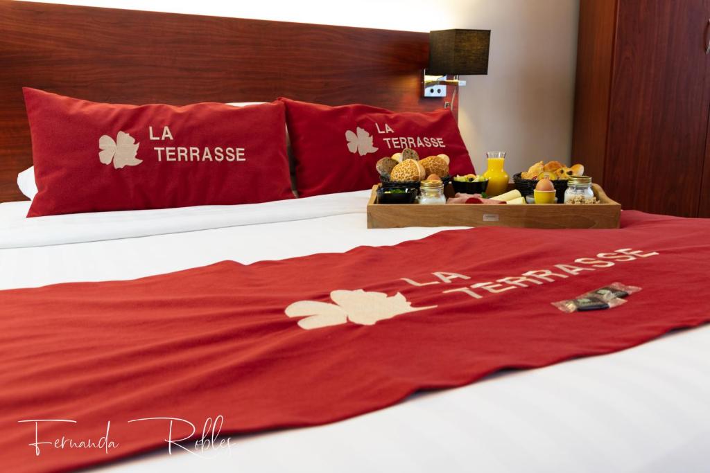 a red blanket on a bed with some food on it at Hotel La Terrasse in De Panne