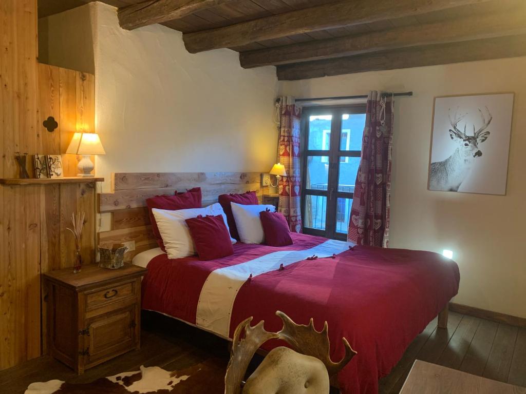 sypialnia z łóżkiem z czerwoną pościelą i oknem w obiekcie Locanda Allevè Hotel Ristorante w mieście Pragelato