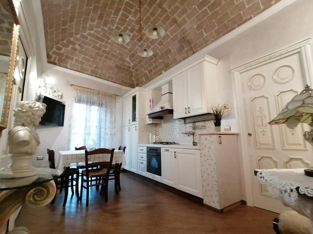 cocina con armarios blancos, mesa y sillas en A Casa di Mamma Rita, en Chieti