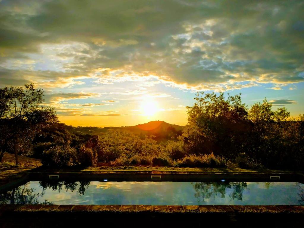 een zonsondergang boven een vijver met zonsondergang op de achtergrond bij Poderi in Chianti in Tavarnelle in Val di Pesa