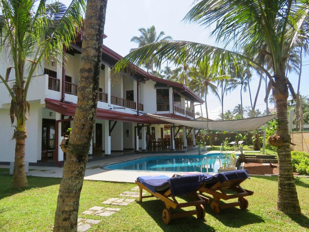 una casa con una hamaca junto a una piscina en Thoduwawa Beach Villa en Paiyagala South