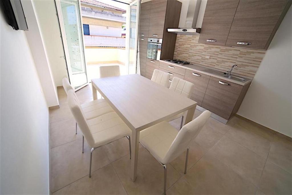 eine Küche mit einem weißen Tisch und weißen Stühlen in der Unterkunft Appartamenti Elite in Martinsicuro