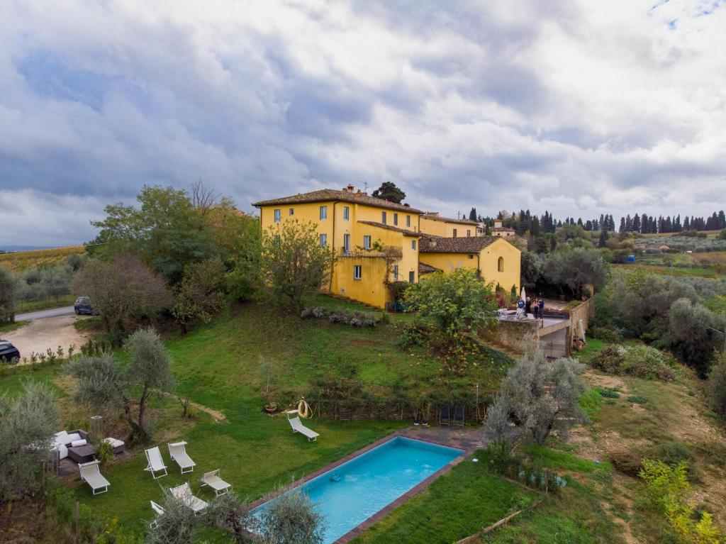 a large yellow house on a hill with a swimming pool at Poderi in Chianti in Tavarnelle in Val di Pesa