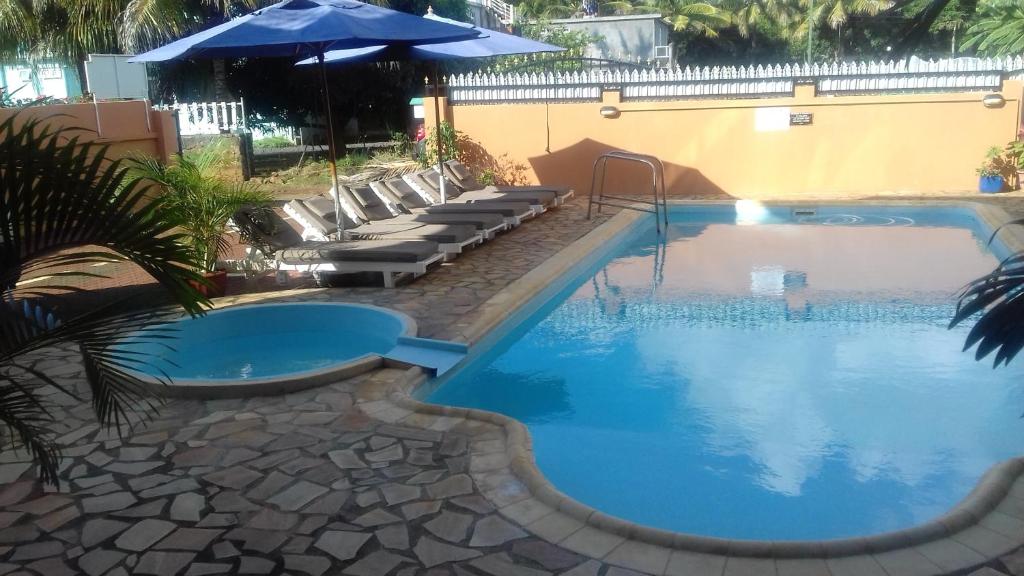 a large swimming pool with chairs and an umbrella at 2 bedrooms appartement at Pointe aux piments 200 m away from the beach with shared pool balcony and wifi in Pointe aux Piments