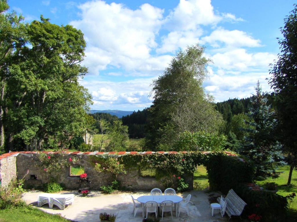 un patio con mesas y sillas en un jardín en Maison de 4 chambres avec jardin amenage et wifi a Saint Andre en Vivarais en Saint-André-en-Vivarais