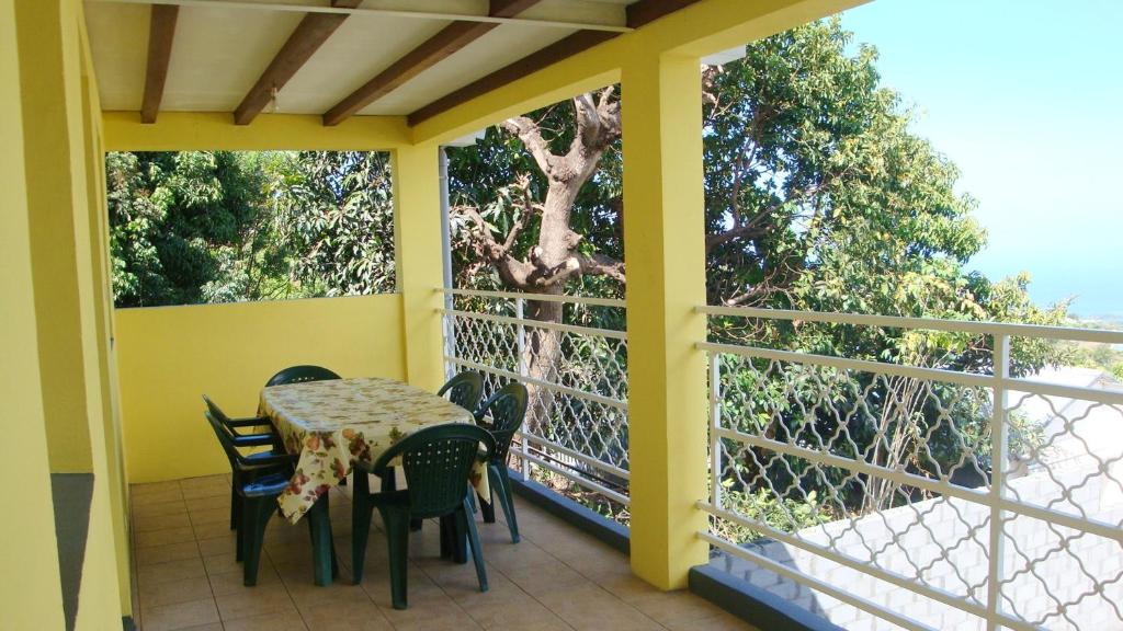 un porche con mesa, sillas y un árbol en Maison de 2 chambres avec vue sur la mer jardin clos et wifi a Saint Paul, en Saint-Paul