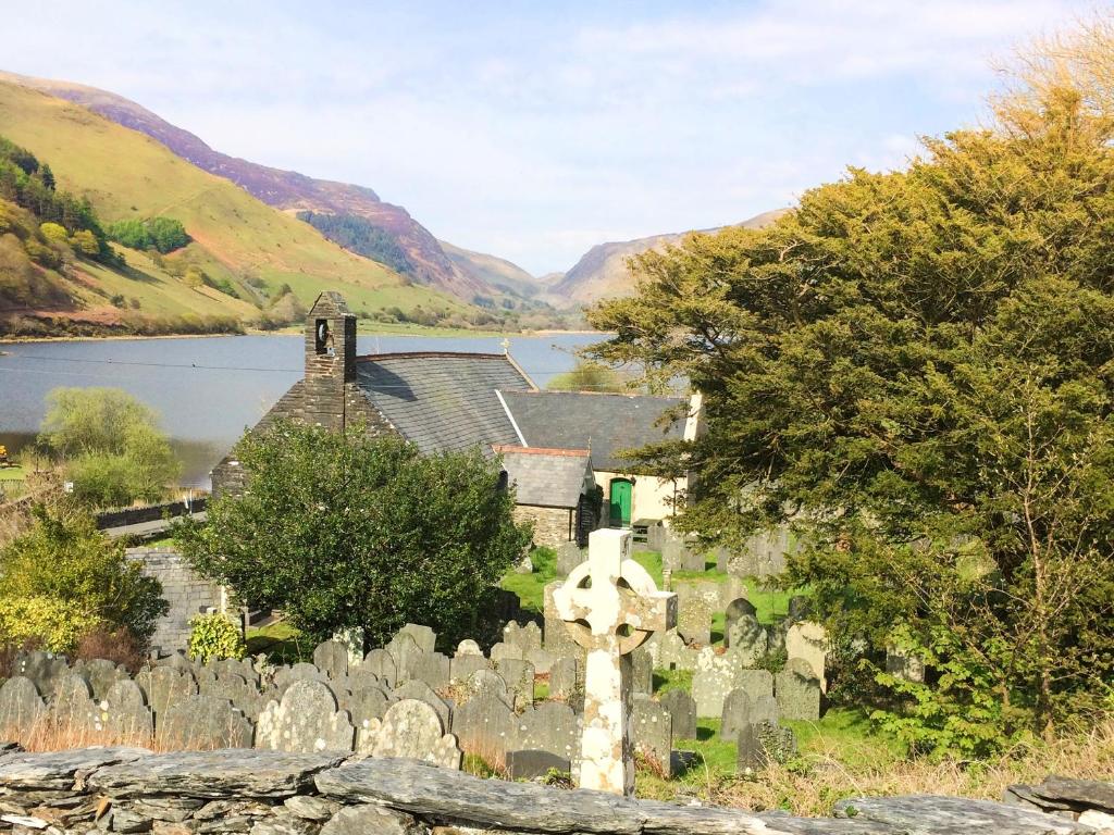 a cemetery with a church and a body of water at St Mary's in Tal-y-llyn