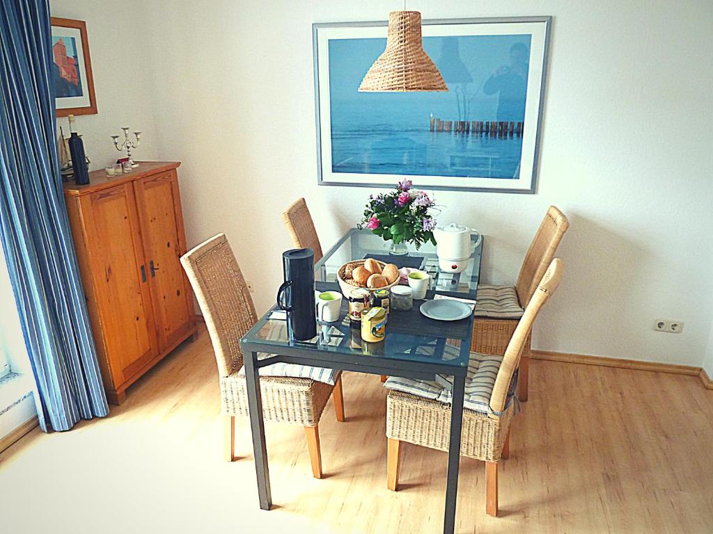 een eettafel met stoelen en een tafel met een fruitschaal bij Villa Silva - Leuchtturmblick in Kühlungsborn