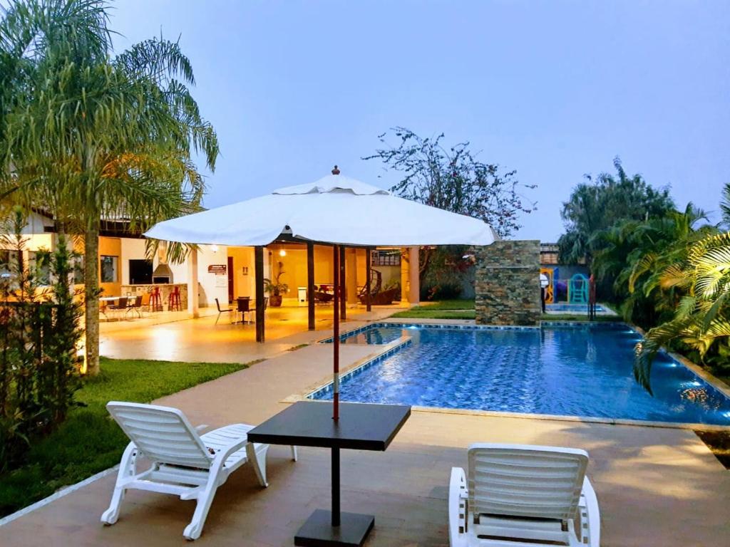 uma mesa com um guarda-sol ao lado de uma piscina em L´acordes Hotel em Porto Velho