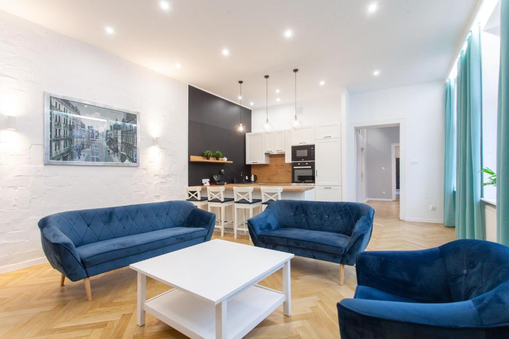 sala de estar con 2 sillas azules y mesa blanca en Victoria Apartment, en Gliwice