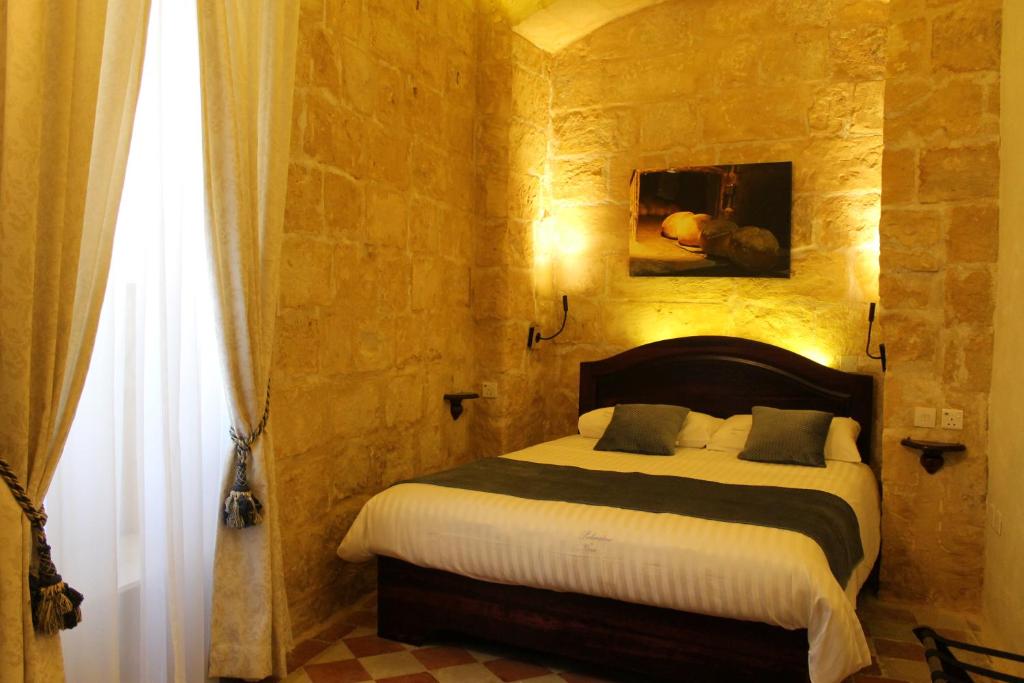 Qormi的住宿－Palazzino Nina Boutique Hotel，卧室配有一张石墙床