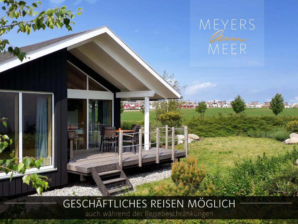 une petite maison noire avec une terrasse couverte et une terrasse dans l'établissement Schwarzes Holzferienhaus mit Sauna -- L I E B L I N G S P L A T Z -- an der Ostsee, Zierow bei Wismar, Strand 500m, alles inklusive, à Zierow