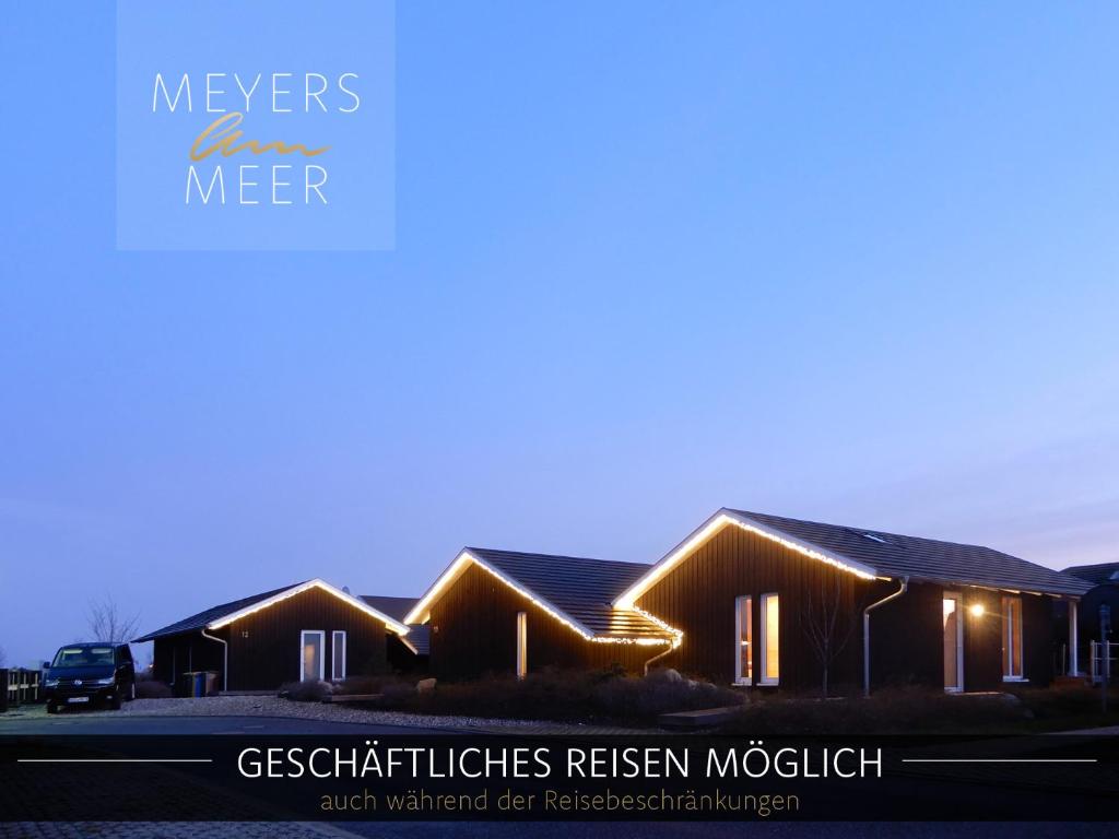 a house with lights on the side of it at Schwarzes Holzferienhaus mit Sauna in Zierow -- SONNENECK -- 500m zum Ostsee-Strand, 4 - 6 Personen in Zierow