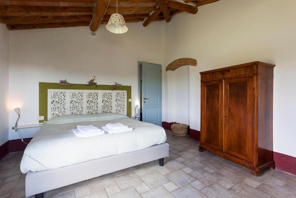 a bedroom with a bed and a wooden cabinet at Poderi in Chianti in Tavarnelle in Val di Pesa
