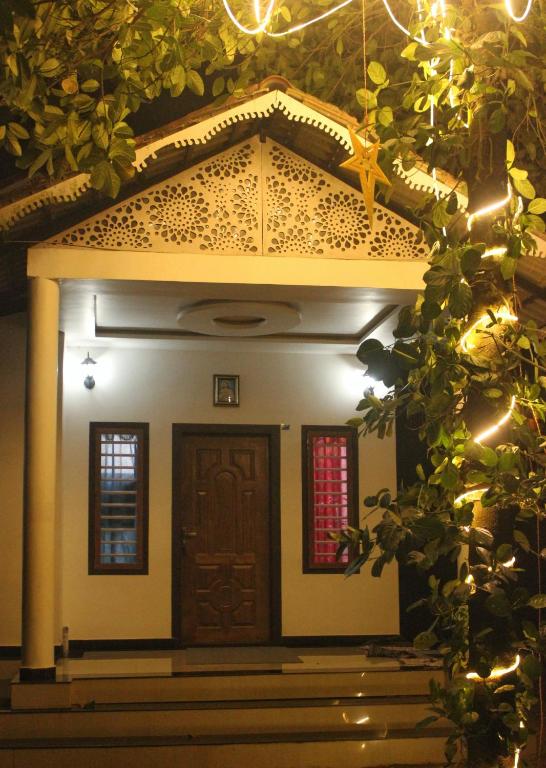 a small house with a wooden door and lights at Wayanad Days in Mananthavady