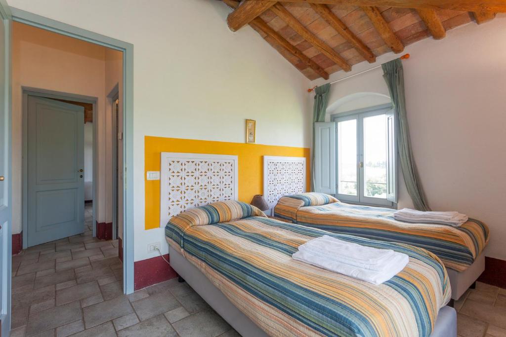 a bedroom with two beds and a window at Poderi in Chianti in Tavarnelle in Val di Pesa