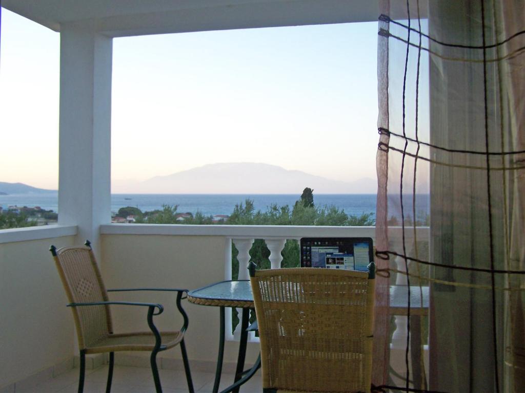 a balcony with a table and chairs and a view of the ocean at Pouliezos Koklanis Zante Apartments in Alykes