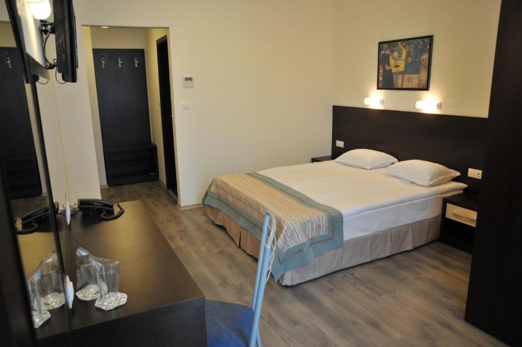 
a hotel room with a bed, chair, and nightstand at Hotel Burgas Free University in Burgas
