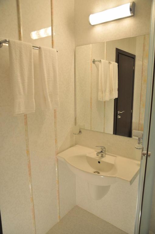a white bathroom with a sink and a mirror at Hotel Burgas Free University in Burgas