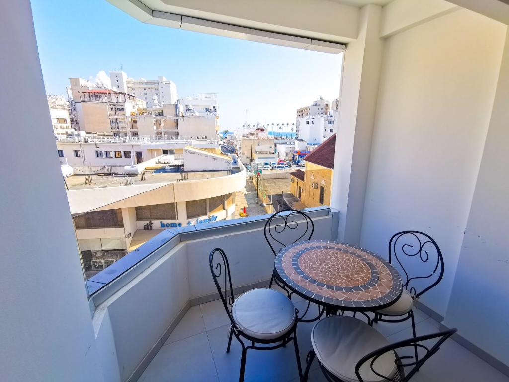 balkon ze stołem i krzesłami oraz dużym oknem w obiekcie Vasilo Court Seaview City Apartment w Larnace