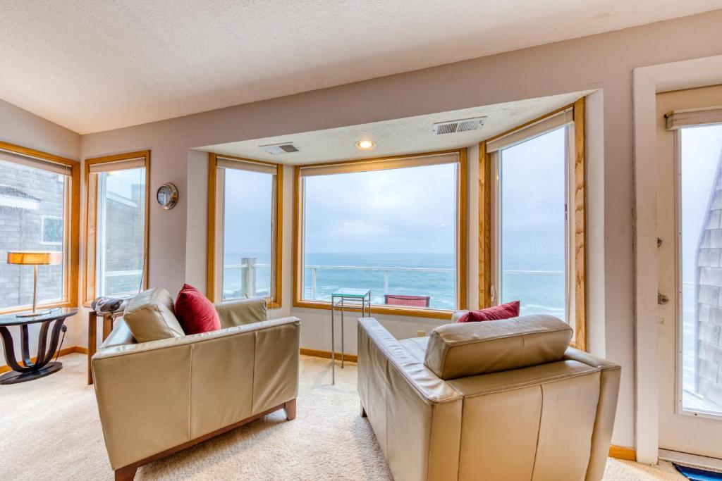uma sala de estar com 2 cadeiras e janelas grandes em Promenade Deck em Depoe Bay