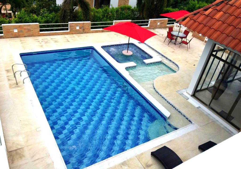 una piscina con una sombrilla roja y una sombrilla roja en Bella Casa Campestre con Piscina Privada Anapoima, en Girardot